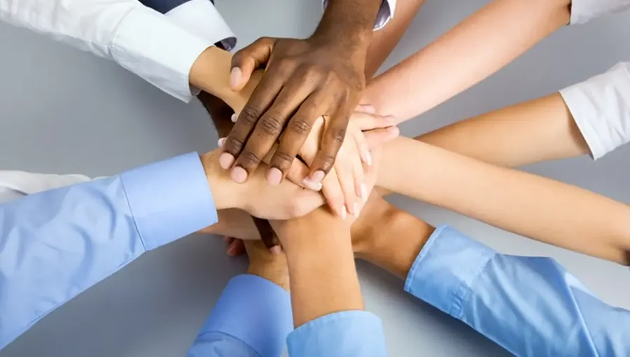 A team stacking their hands together in a huddle